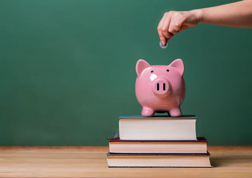 placing money in a piggybank for education costs and tuition planning