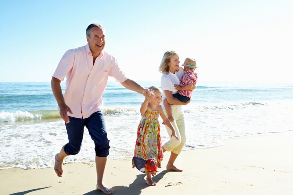 retirement age couple playing with grandchildren on the beach