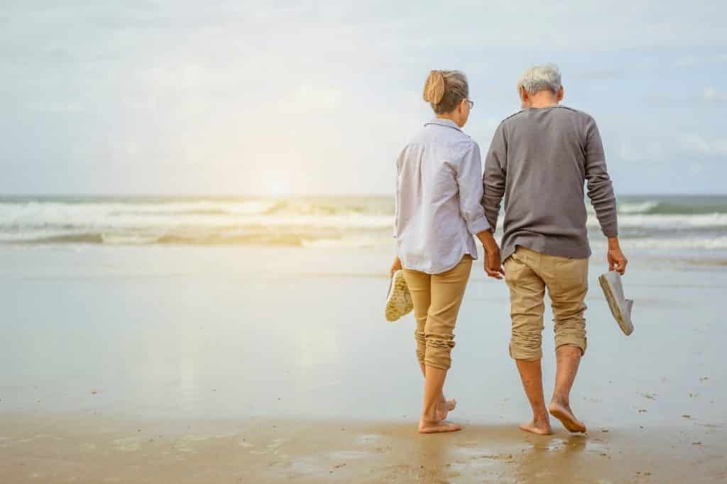 retired couple walking on the beach