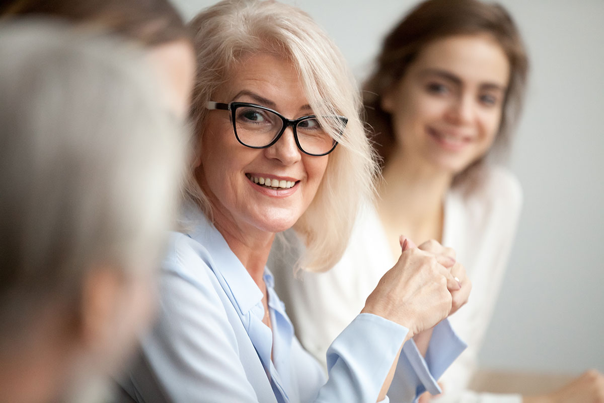 older woman in professional clothing smiling in a retirement plan meeting