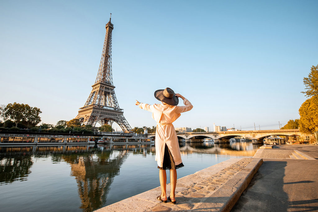 woman on vacation in front of the eiffel tower to represent financial tips for traveling