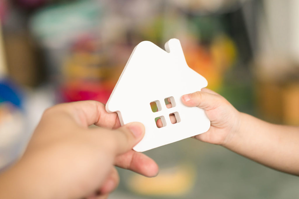 parent handing a child a plastic house to represent legacy planning