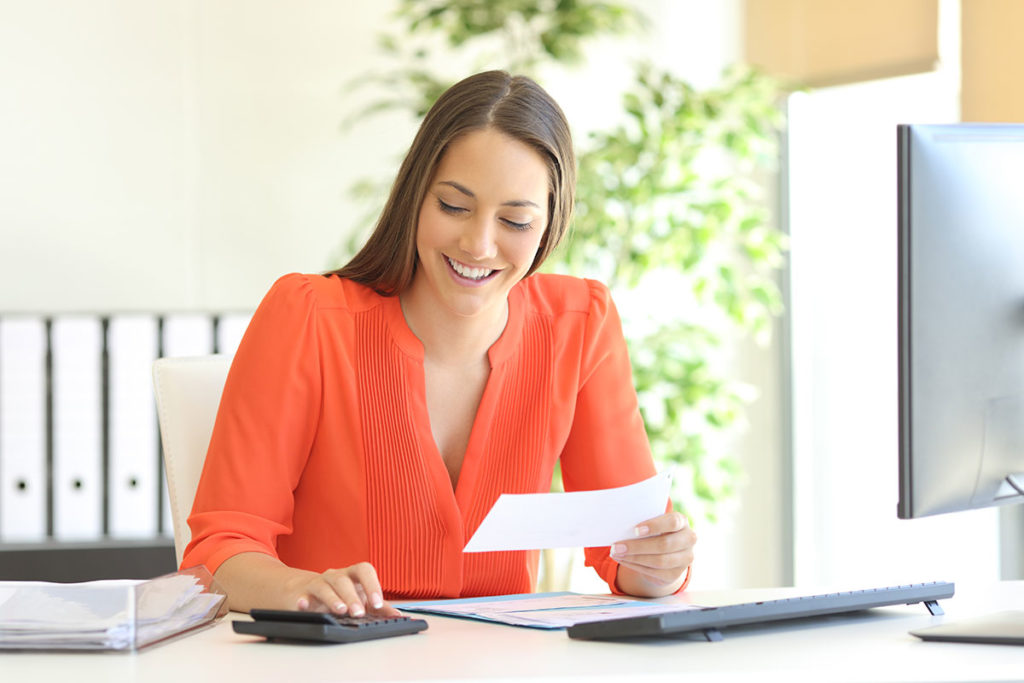 young woman in a bright orange blouse looking over tax deductions