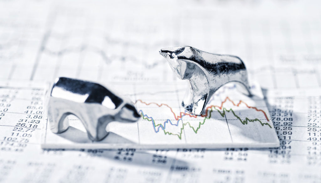 bear and bull figurines on a stock market graph