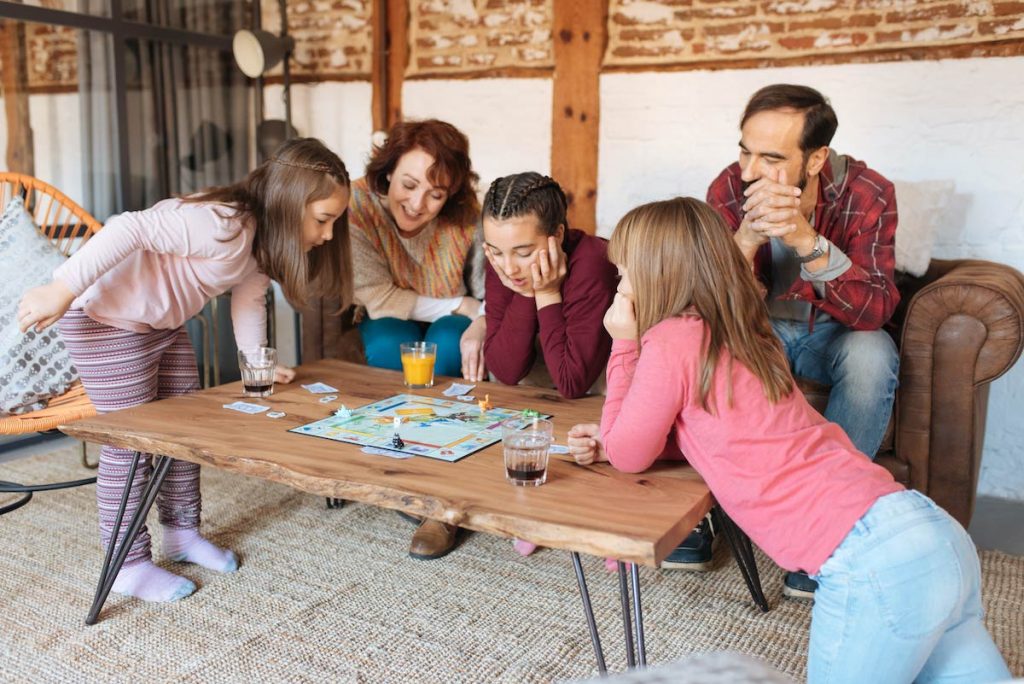 family gathered around table playing board game financial freedom